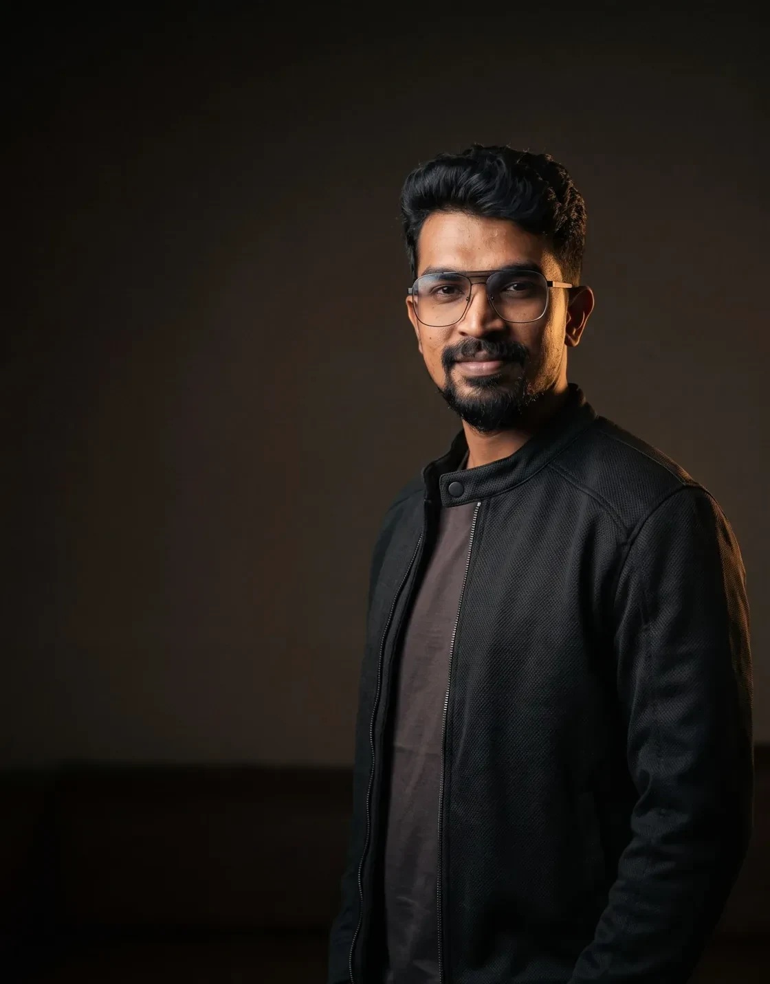 Chennai performance marketer in a black jacket photographed in a dark studio with soft warm key light