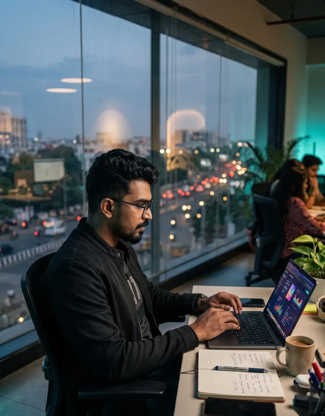 Reviewing campaign reports Digital marketing agency founder reviewing campaign reports on a laptop beside a city-view office window in Chennai