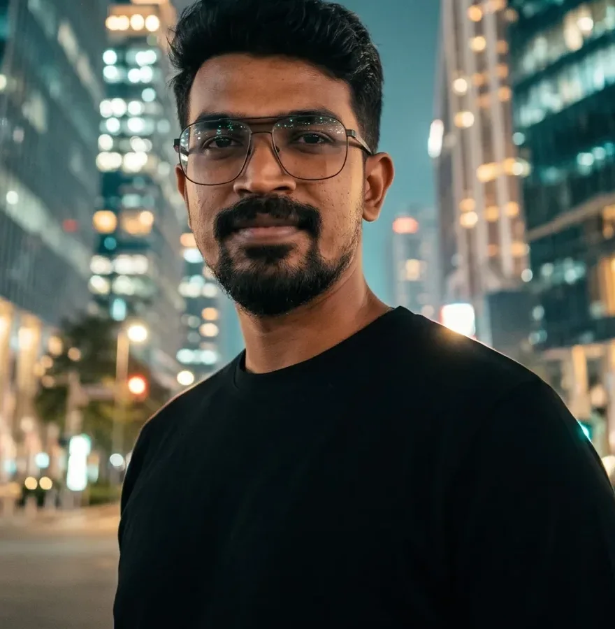 Close portrait of Digital Raghavan on a Shenzhen bridge at night with towers lit behind him