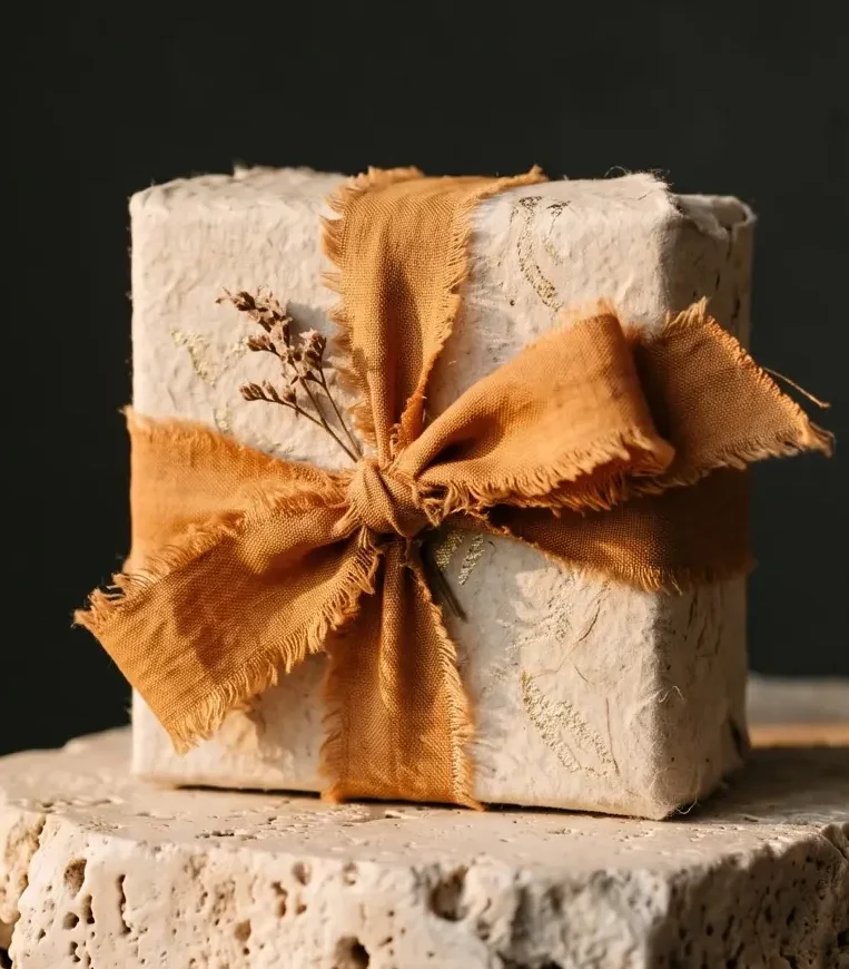 Close-up of an orange ribbon bow Close-up of an orange ribbon bow on a stone gift box with dried flowers, AtherFlow Chennai
