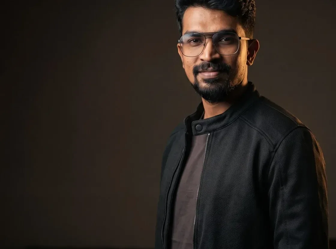 Half length wide portrait of a performance marketer in a black jacket against a dark studio wall
